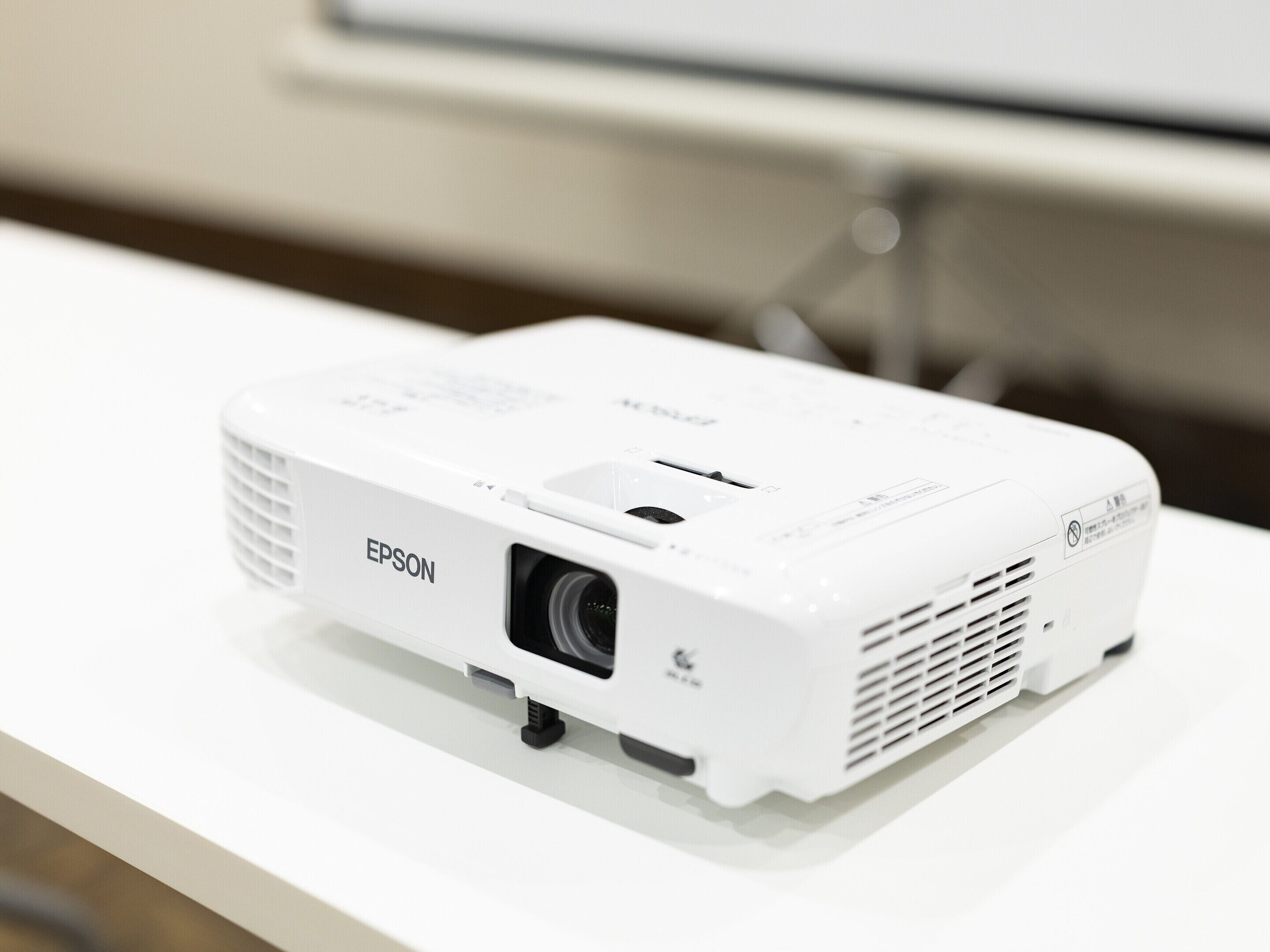 Un proyector Epson blanco sobre una superficie blanca.