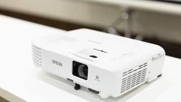 Un proyector Epson blanco sobre una superficie blanca.