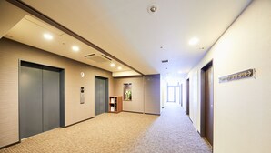 Un pasillo con piso alfombrado, puertas y un cartel con los números de las habitaciones.