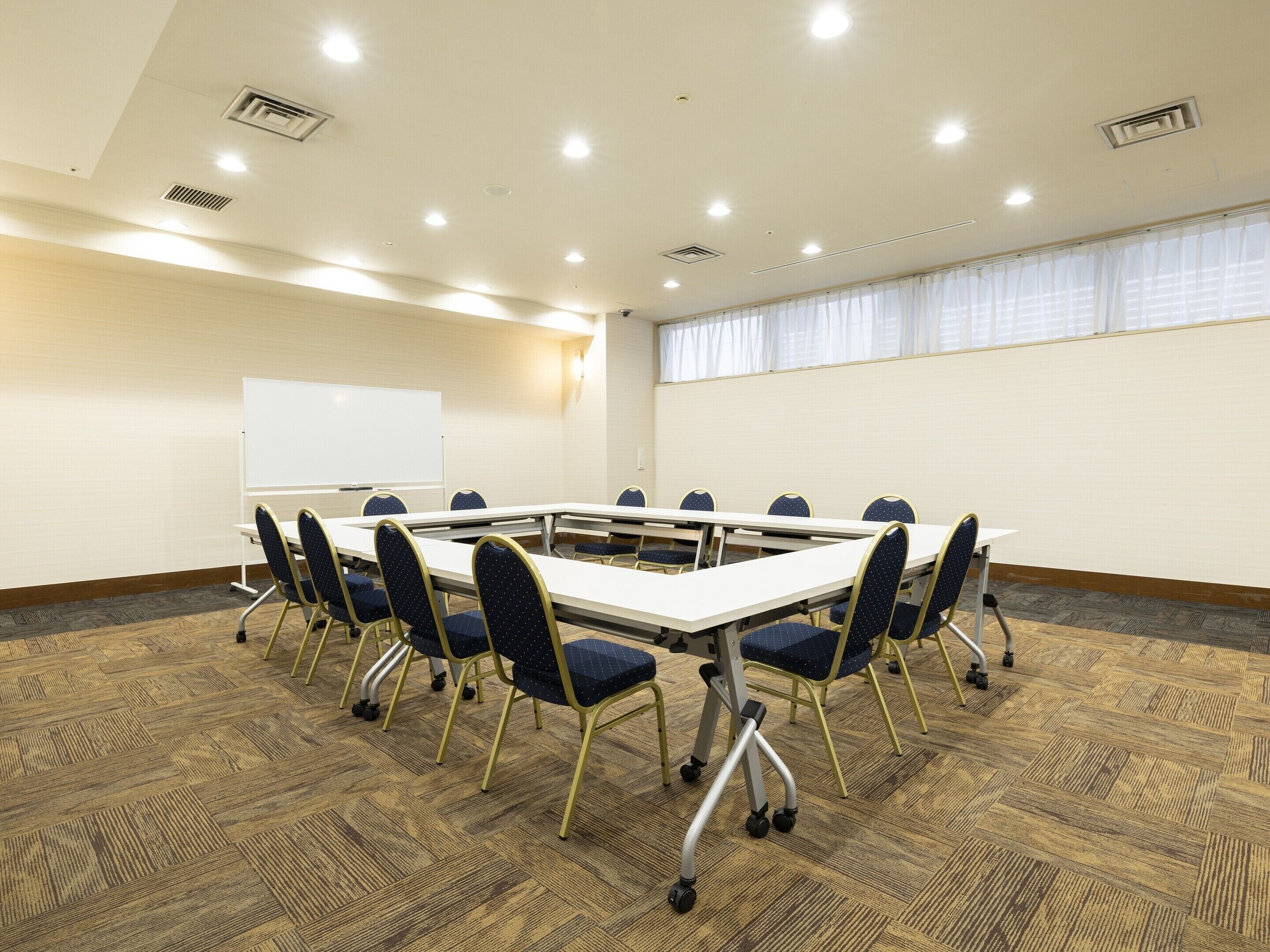 A conference room with a large table, chairs, a whiteboard, and a carpeted floor.
