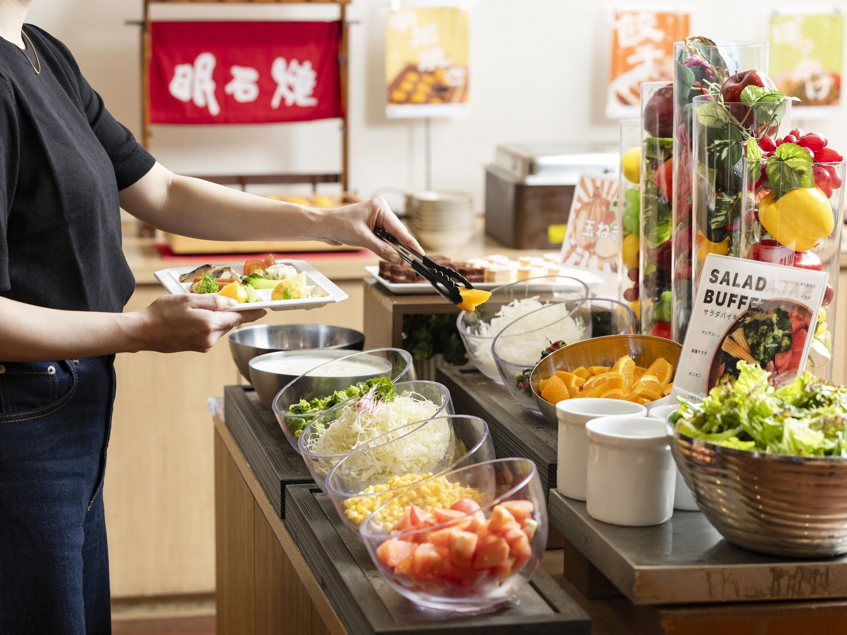 Un buffet proposant une variété de plats, notamment des salades, des légumes et des fruits.