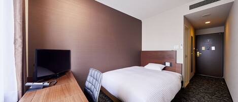 A hotel room with a bed, a desk with a computer, a chair, and a television.