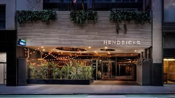 Een hotelentree met een modern design, met een houten gevel, een terras en een goed verlichte ingang.