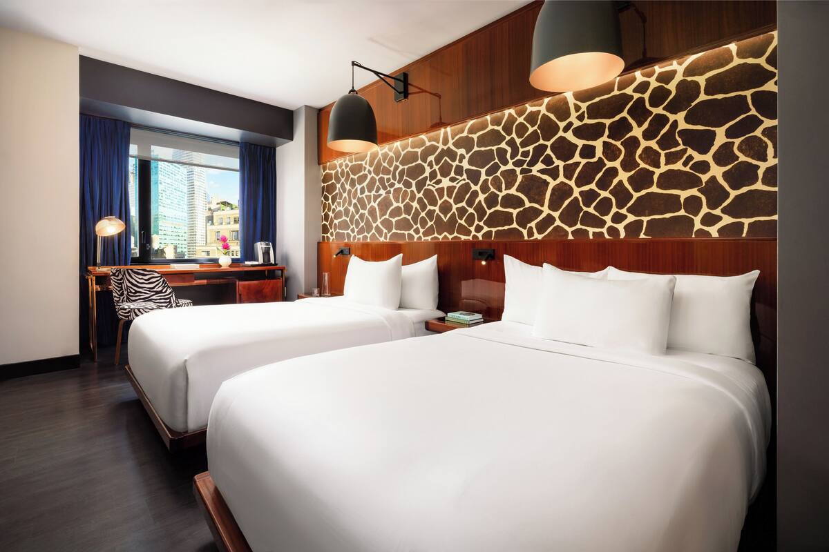 Hotellihuone, jossa on kaksi sänkyä, työpöytä ja näköala kaupunkiin.