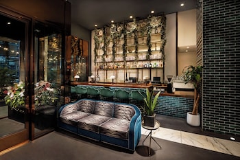 A modern hotel entrance with a glass door, a reception desk, and a seating area visible through the glass. at Hotel Hendricks