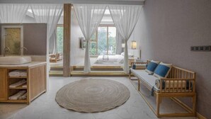 A modern bedroom with a large window, a wooden bench, a round rug, and a wooden cabinet with towels. - Floral Hotel South Luogu Lane 20 Mansion (Beijing)