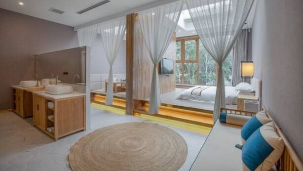 A modern bedroom with a large window, a wooden vanity, a bed with a view, and a bedside table with a lamp. - Floral Hotel South Luogu Lane 20 Mansion (Beijing)