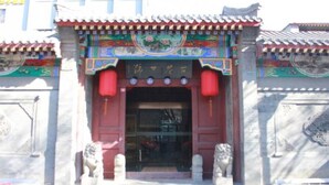 A traditional building with a red entrance, ornate decorations, and stone lion statues. - Floral Hotel South Luogu Lane 20 Mansion (Beijing)