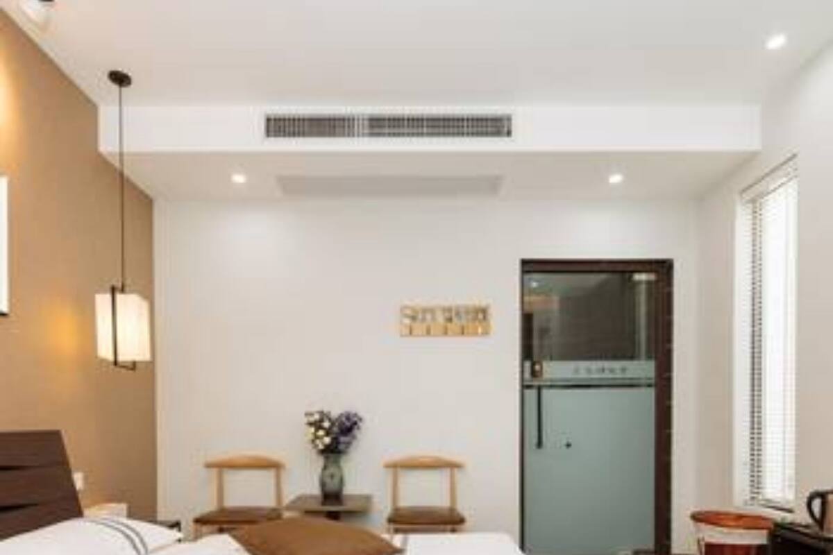 Ein modernes Hotelzimmer mit einem großen Bett, Nachttischen, einem kleinen Schreibtisch, einem Kühlschrank und einem Fenster mit Jalousien.