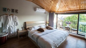 A bedroom with a wooden ceiling, a large bed with pillows, a nightstand, a basket, and a view of the outdoors through a balcony. - Floral Hotel Nanjing Zuolingyoushe (Nanjing)