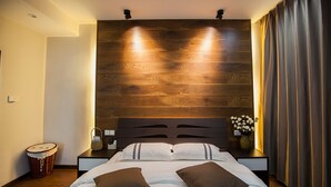 A modern bedroom with a wooden headboard, a large bed with two pillows, a bedside table with a vase of flowers, and a nightstand with a lamp. - Floral Hotel Nanjing Zuolingyoushe (Nanjing)