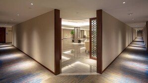 A hotel corridor with a modern design, featuring a central column, a reception area, and a patterned carpet. - Changshu Skyline Cloud Hotel (Suzhou)