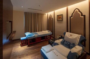 A room with a massage table, a massage chair, and a small table with a book.