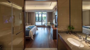 A hotel room with a bed, a desk, a large mirror, and a bathroom with a sink. - Changshu Skyline Cloud Hotel (Suzhou)