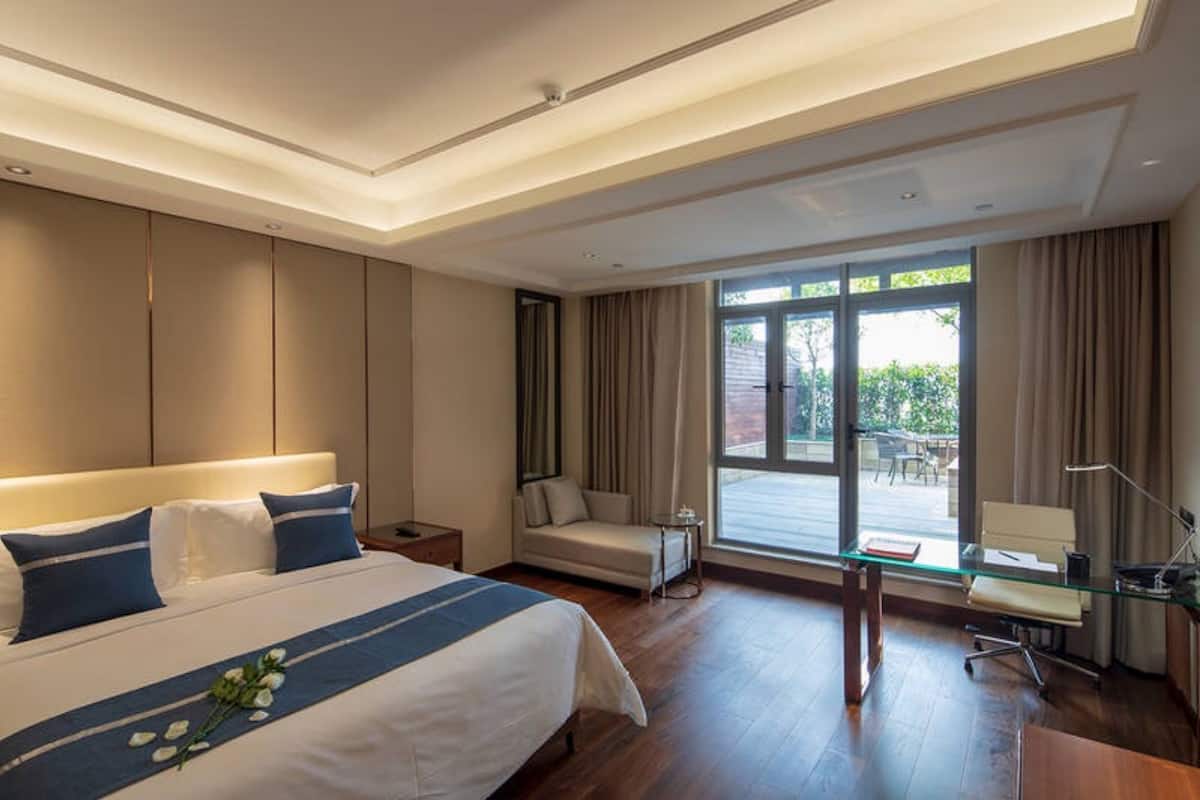 Una habitación de hotel moderna con una cama grande, un escritorio y vistas al exterior.
