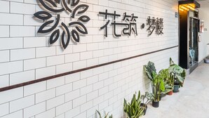 A reception area with a white tiled wall, a logo, and potted plants. - Floral Hotel Xiamen Menglou (Xiamen)