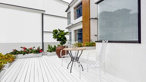 A modern outdoor patio with a wooden table and chairs, surrounded by potted plants and flowers. - Floral Hotel Xiamen Buxiang Inn (Xiamen)