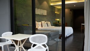 A modern hotel room with a glass partition, a bed, a small table, and two chairs. - Floral Hotel Ningbo Zhuye (Ningbo)