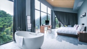 A modern bedroom with a large bed, a sitting area, and a bathtub. - Floral Hotel Ningbo Zhuye (Ningbo)