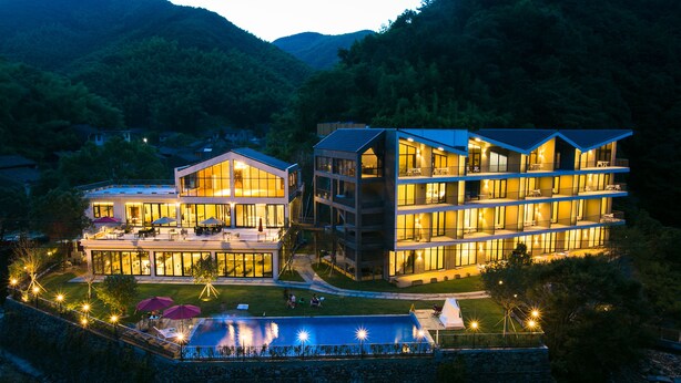 A modern hotel with multiple floors, outdoor seating, and a swimming pool. - Floral Hotel Ningbo Zhuye (Ningbo)