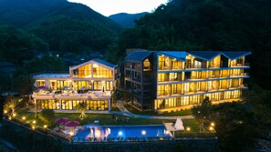 Un hotel moderno con varios pisos, zona de estar exterior y piscina.