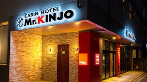 Exterior del Hotel Cabin Mr. Kinjo, con fachada de piedra, puerta de madera y señalización iluminada.