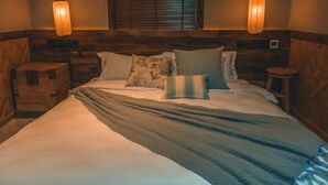 A bedroom with a wooden headboard, two bedside tables, a bed with multiple pillows, and two hanging lantern-style lights. - Floral Hotel Ningbo Shieryi Hotspring (Ningbo)
