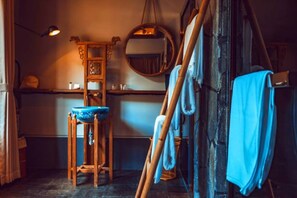 A rustic bathroom with a wooden basin, a mirror, and a towel rack.