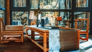 A cozy reading nook with a wooden table, wicker chairs, and a large window with bookshelves. - Floral Hotel Ningbo Shieryi Hotspring (Ningbo)