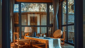 A room with a large window, a wooden table, chairs, and a woven basket. - Floral Hotel Ningbo Shieryi Hotspring (Ningbo)