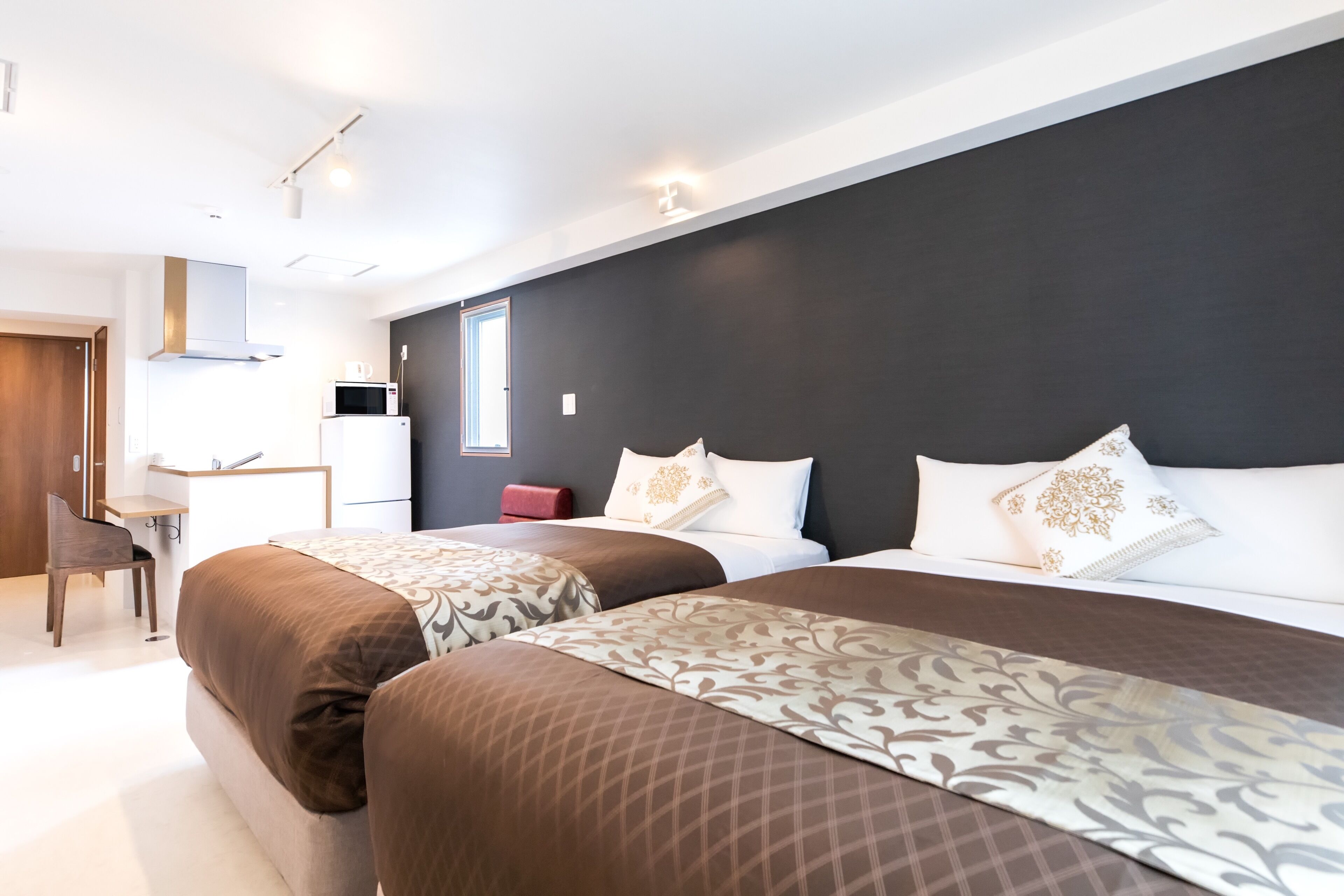 A hotel room with two beds, a desk, and a chair.