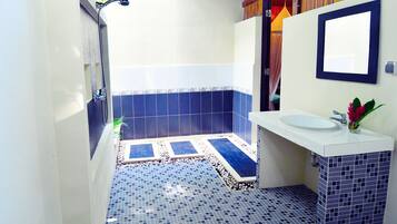 A bathroom with a white sink, blue-tiled floor, and a shower area.