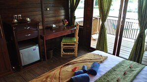 Hotellihuone, jossa on sänky, pieni työpöytä, tuoli ja jääkaappi.