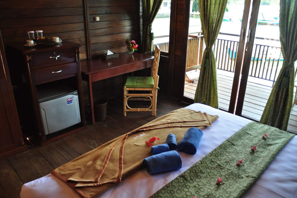 Una habitación de hotel con una cama, un escritorio pequeño, una silla y un refrigerador.