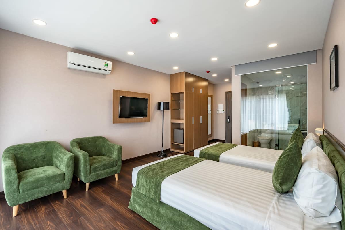Quarto de hotel com duas camas, uma televisão, um guarda-roupa e um aparelho de ar condicionado.