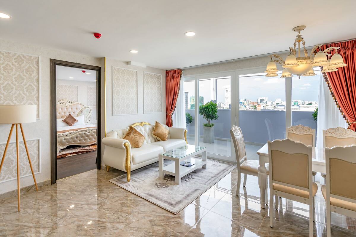 Uma sala de estar ampla com uma cama grande, um sofá, uma mesa de centro e um espaço de refeições com cadeiras.
