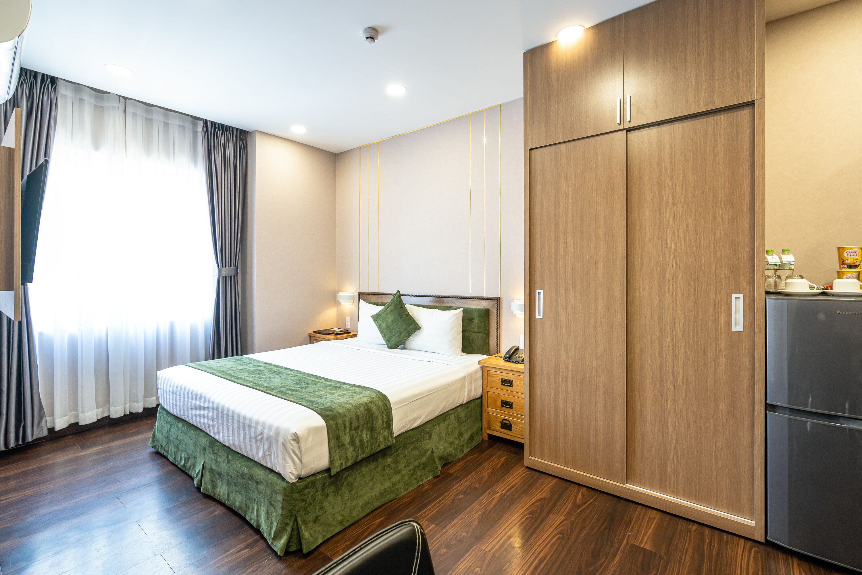 Una habitación de hotel con cama, armario, mesita de noche y refrigerador.