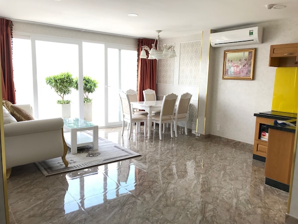 A modern living room with a dining area, large windows, and a marble floor.
