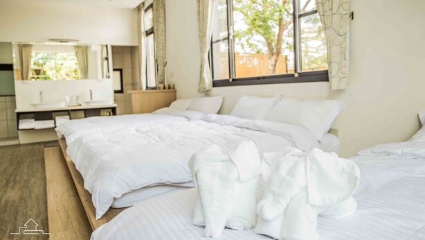 A hotel room with a large bed, a bedside table, a mirror, and a window with curtains. - shih.kuang (Tainan)