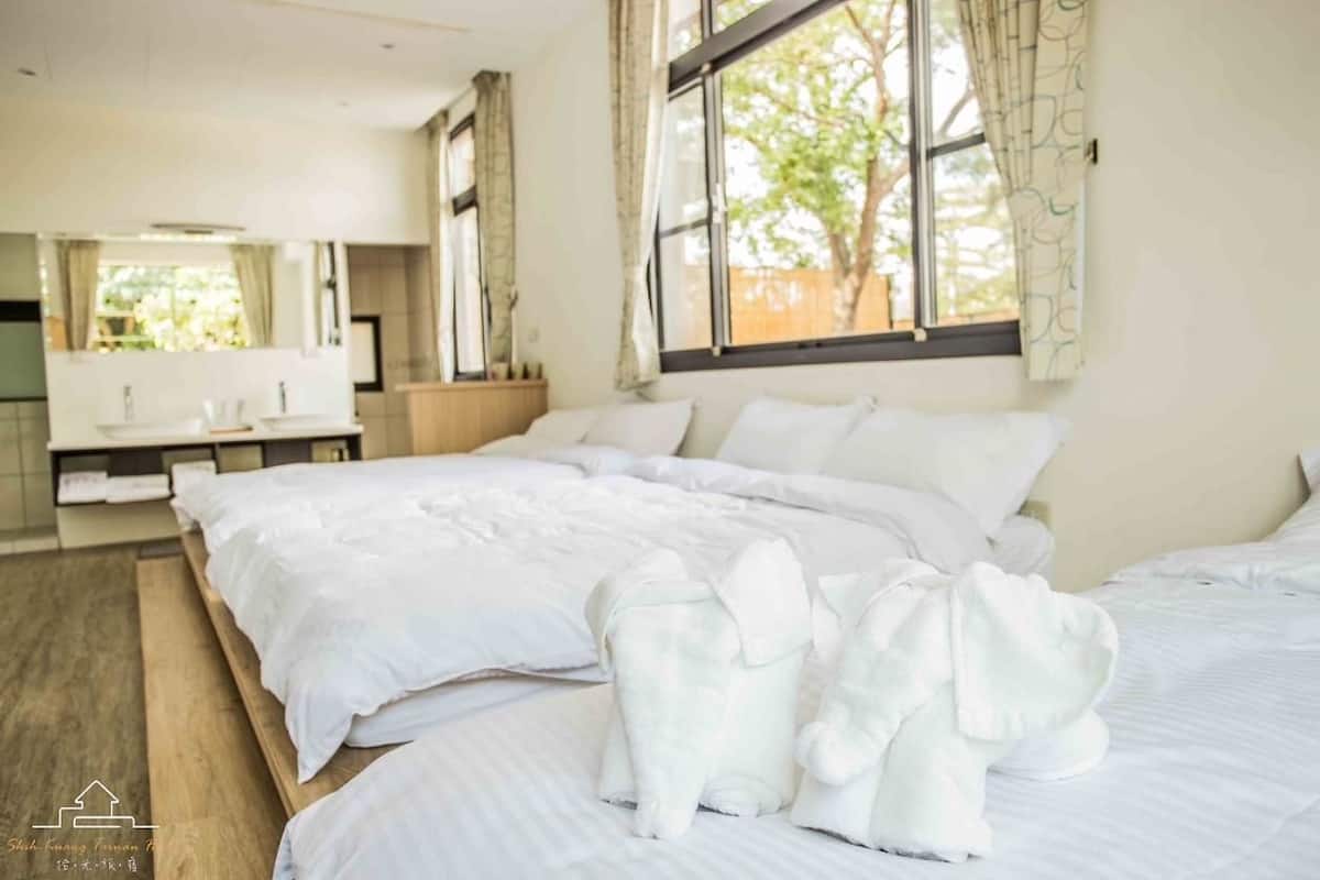 Quarto de hotel com uma cama grande, uma mesa de cabeceira, um espelho e uma janela com cortinas.