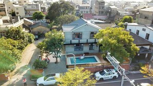 A residential area with a two-story house featuring a swimming pool, a car parked in front, and a person standing by the pool. - shih.kuang (Tainan)