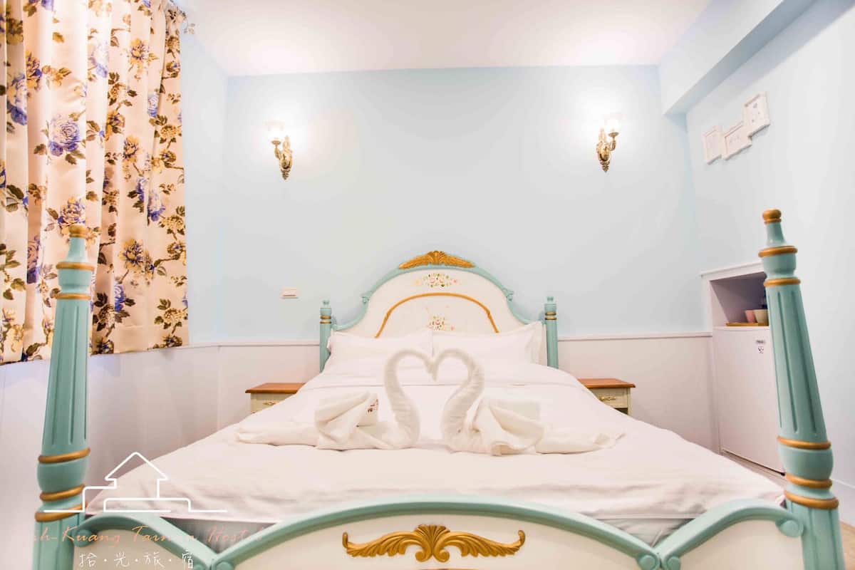 Uma cama com cabeceira decorativa e um arranjo de almofadas em formato de cisne.