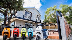 A row of colorful scooters parked in front of a building with a balcony. - shih.kuang (Tainan)