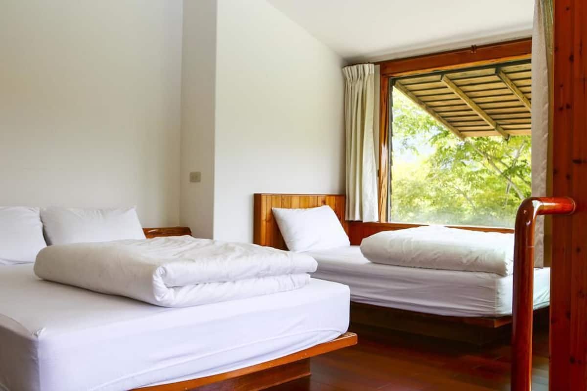 Habitació amb dos llits, ambres de fusta, roba de llit blanca i una finestra amb cortines.