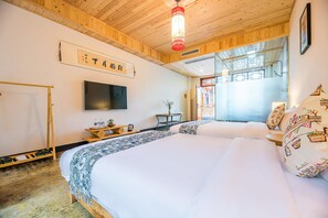 A hotel room with a large bed, a TV mounted on the wall, a wooden ceiling, and a window with a view.