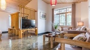 A spacious living room with a wooden TV stand, a large flat-screen TV, a wooden coffee table, and a comfortable sofa. - Floral Hotel Chengdu Dujiangyan (Chengdu)