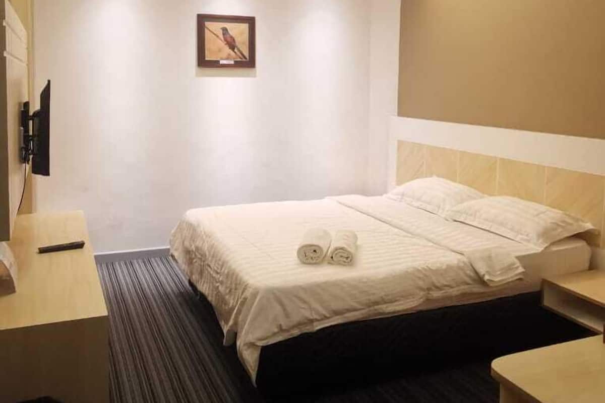 Ein Hotelzimmer mit Bett, Schreibtisch, Stuhl, Fernseher und einem Bild an der Wand.
