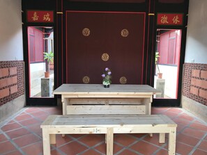 A wooden bench with a small table in front of a red door with gold decorations.