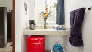 Ein Badezimmer mit Dusche, einer Kaffeemaschine, einer Vase mit Blumen, einem Handtuch und einem roten Gerät.