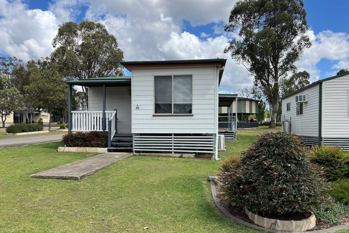 A small, single-story mobile home with a porch and a number '38' sign.